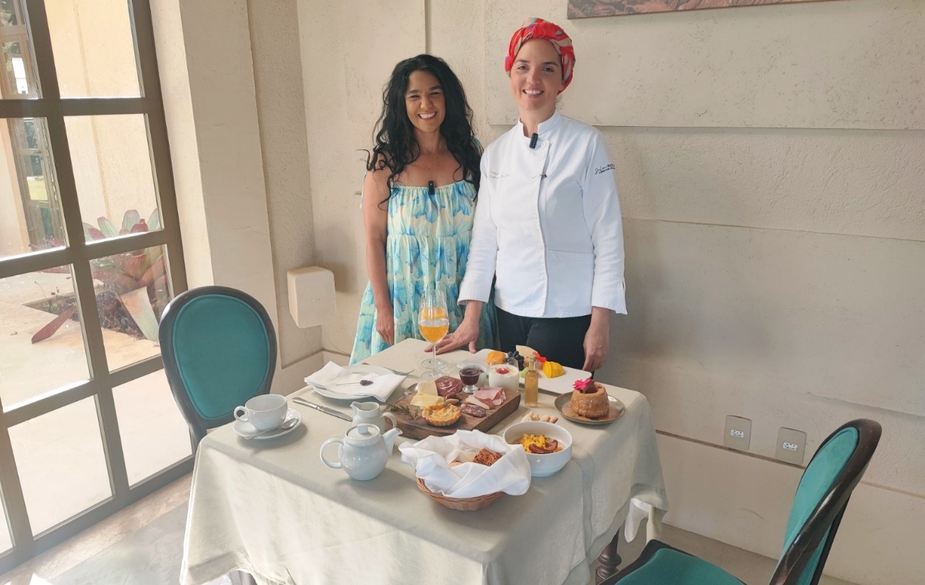 Geylla Sall e a chef da Pousada Manacás diante de uma mesa de café da manhã